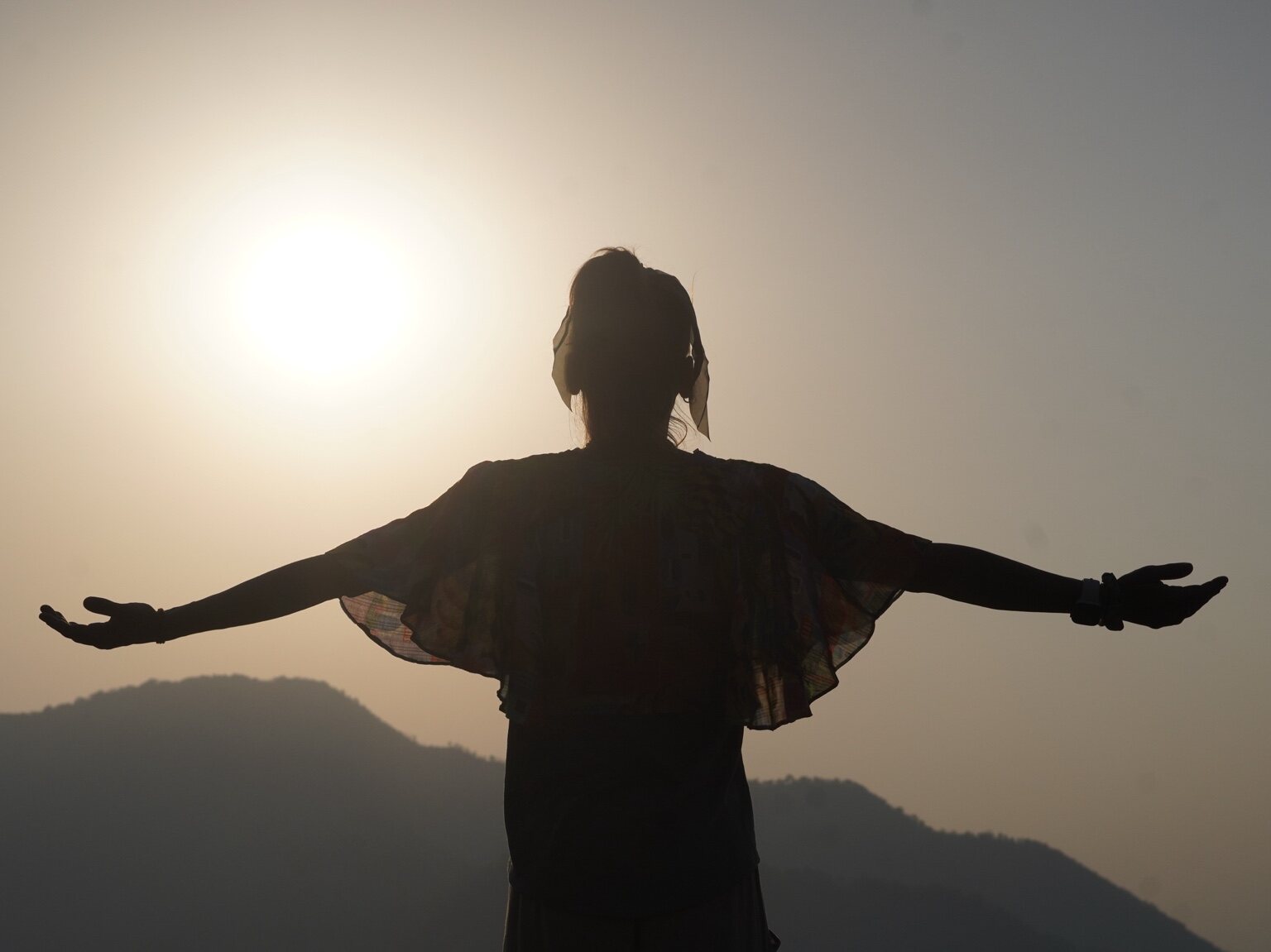 Vanessa standing with her arms open at sunrise in Rishikesh
