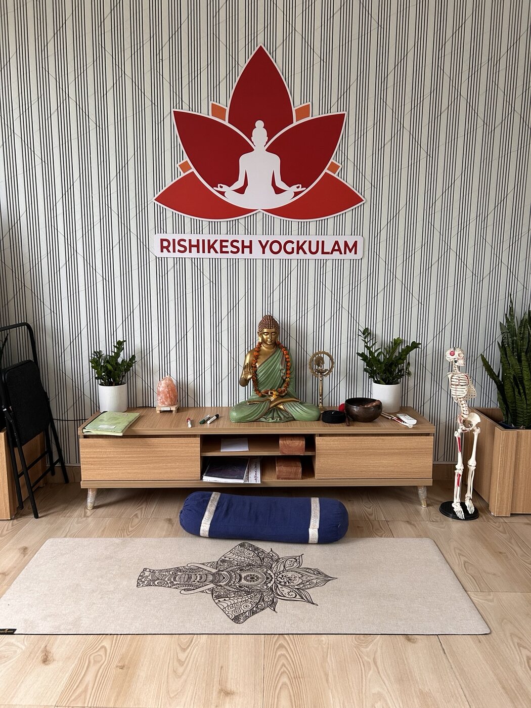 The practice room at Rishikesh Yogkulam with a yoga mat, Buddha statue and anatomy model